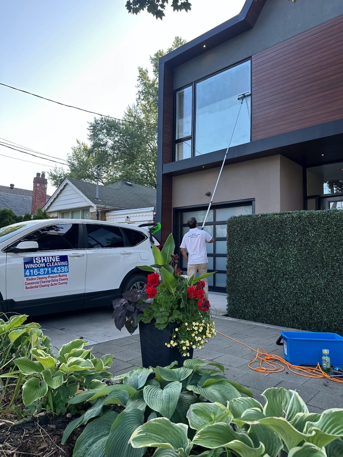 iShine technician using a water-fed pole to clean high windows on a Toronto home